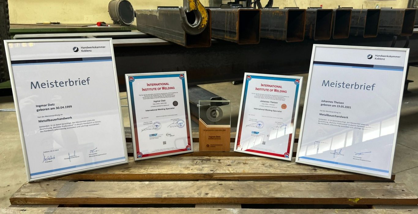 Zertifikate auf einem Tisch, darunter auch ein Preis und ein Ehrenurkunde.