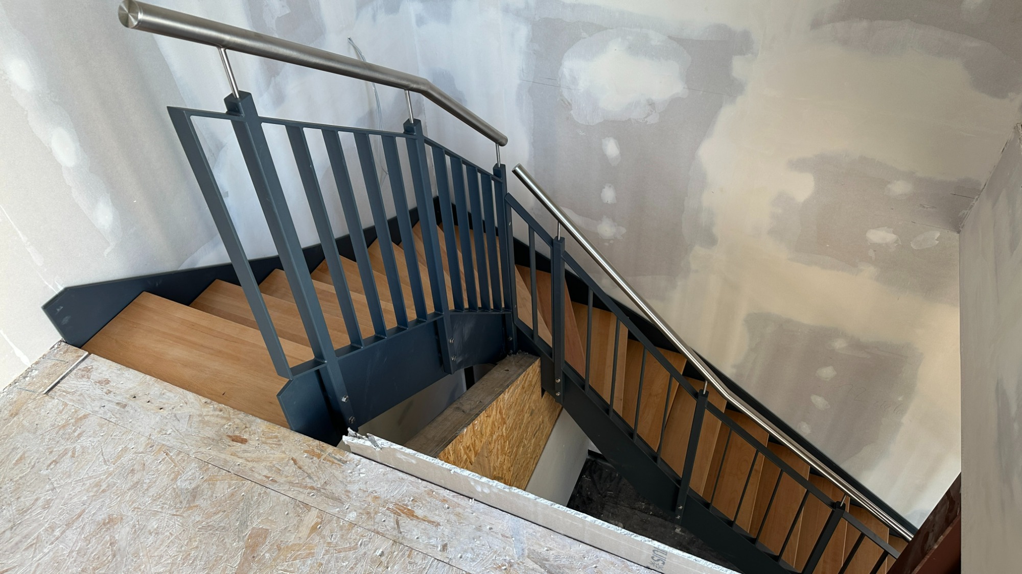 Gewendelte Flachstahltreppe mit Buchenholzstufen und Edelstahlhandlauf